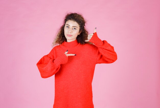 donna in camicia rossa che mostra il segnale di chiamata.