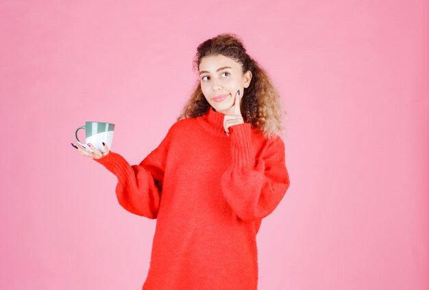 donna in camicia rossa che tiene una tazza di caffè.