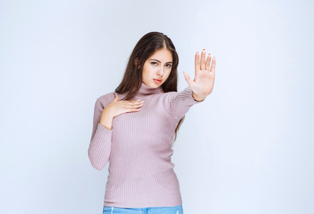 donna in camicia viola che rifiuta qualcosa con gesti di mano.