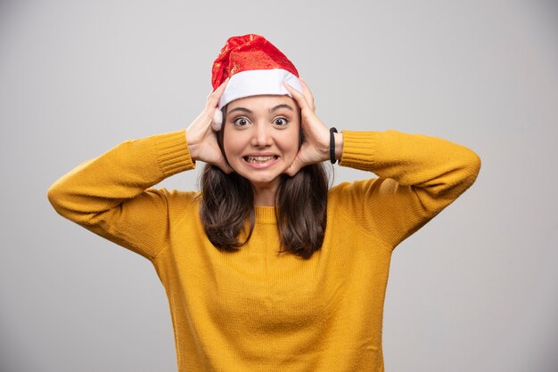 Donna in cappello della Santa che tiene il suo fronte sul muro grigio.