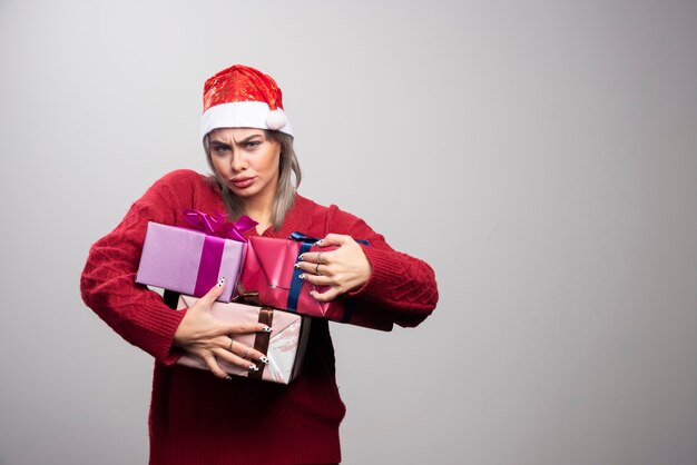 Donna in cappello della Santa che tiene mazzo di scatole regalo.