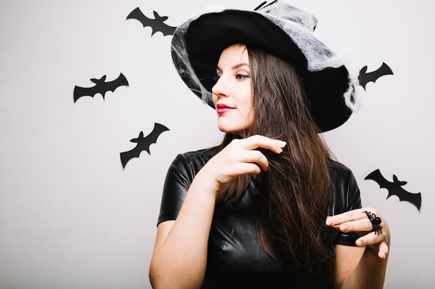 Donna in cappello di Halloween che gioca con i capelli