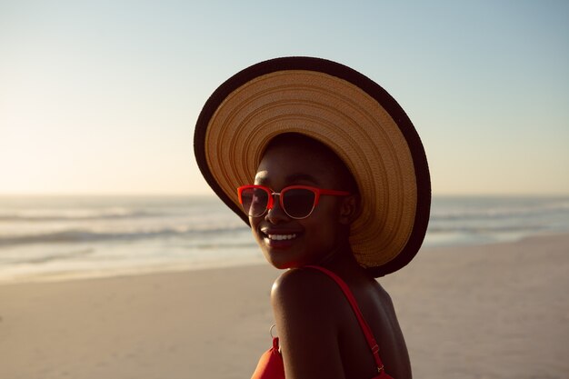 Donna in cappello e occhiali da sole che si rilassano sulla spiaggia