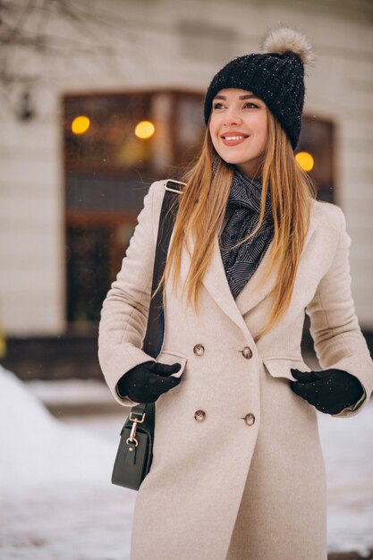 Donna in cappotto in piedi fuori dal caffè in una strada d&#39;inverno