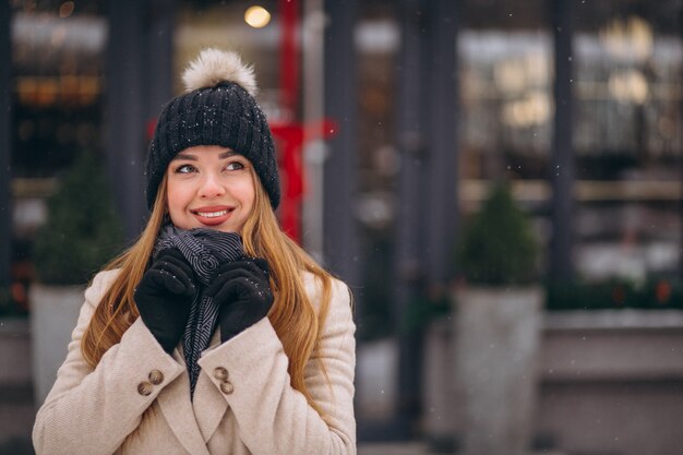 Donna in cappotto in piedi fuori dal caffè in una strada d&#39;inverno