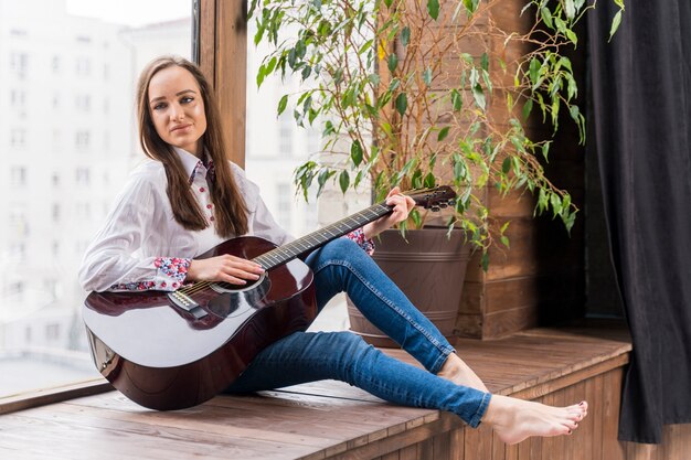 Donna in casa a suonare la chitarra