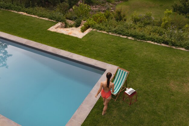 Donna in costume da bagno vicino al bordo piscina nel cortile