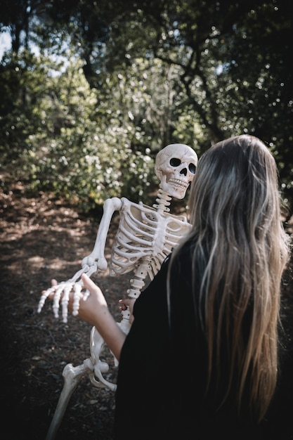 Donna in costume da strega piegando lo scheletro