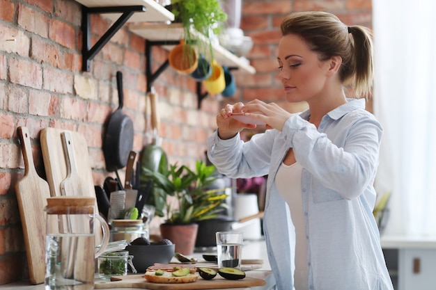 Donna in cucina a mangiare un panino