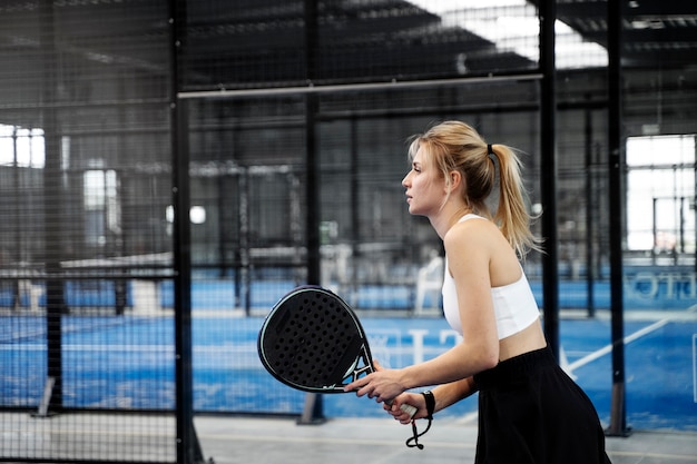 Donna in forma di tiro medio che gioca a paddle tennis