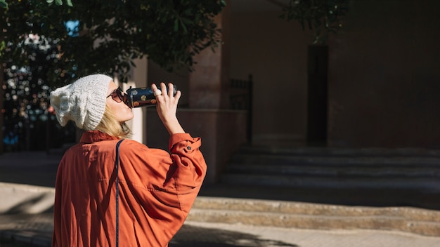 Donna in giacca arancione che beve dal thermos