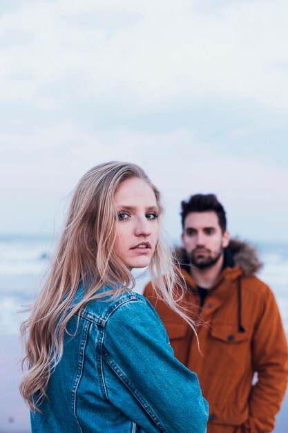 Donna in giacca di jeans vicino a uomo sulla spiaggia