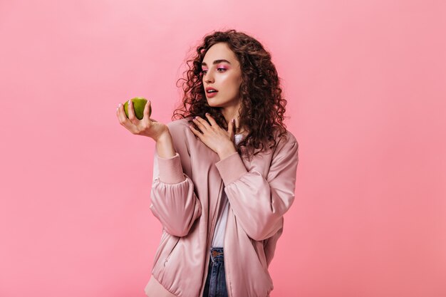 donna in giacca rosa guarda Apple su sfondo isolato