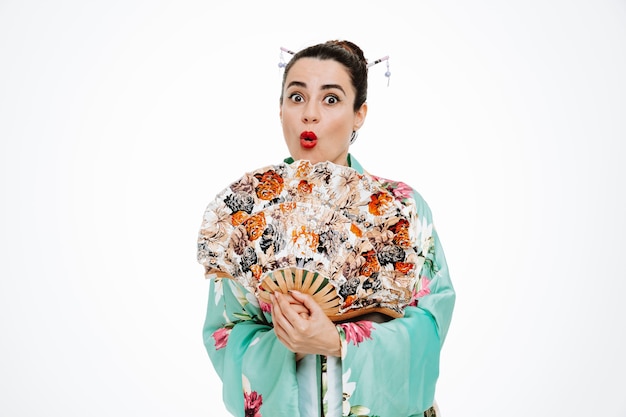 Donna in kimono tradizionale giapponese che tiene in mano un ventaglio stupito e sorpreso su bianco