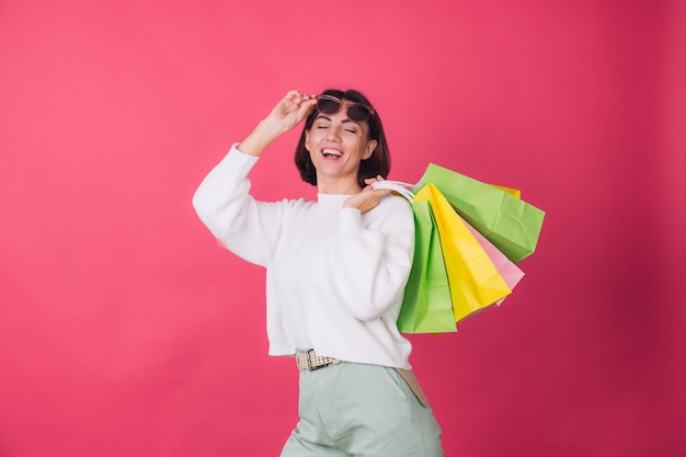 Donna in maglione bianco casual e occhiali da sole sulla parete rossa