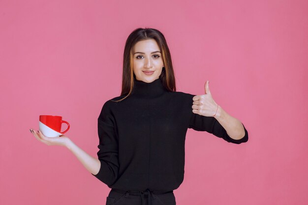 Donna in maglione nero, bere un caffè e godersi il gusto.