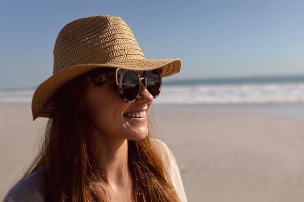 Donna in occhiali da sole e cappello rilassante sulla spiaggia