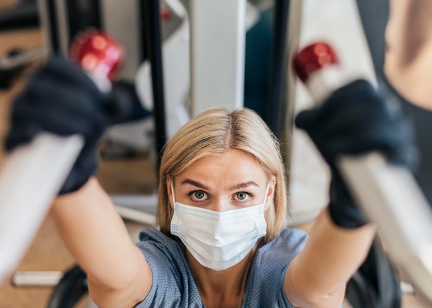 Donna in palestra utilizzando attrezzature con maschera