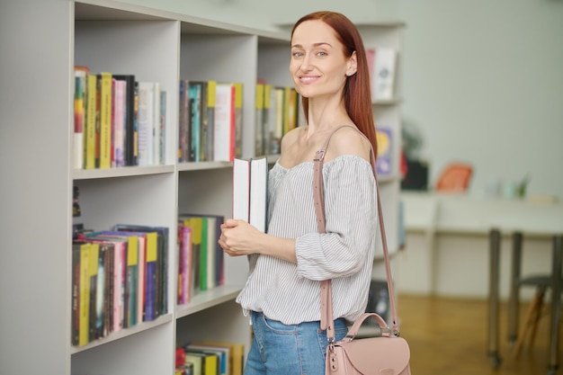 Donna in piedi con i libri che guarda l'obbiettivo