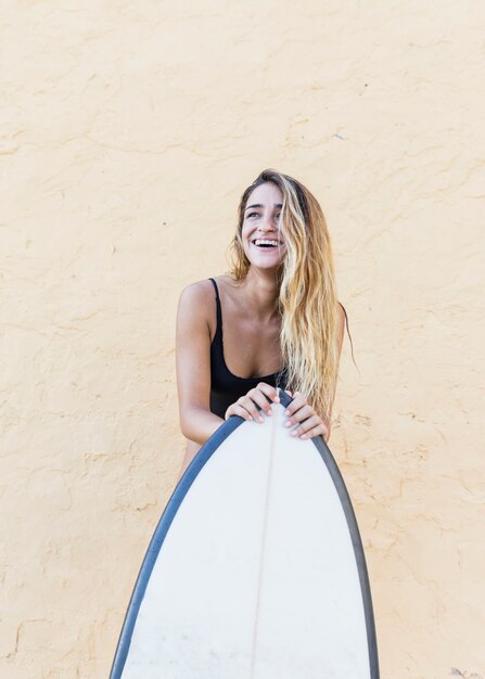 Donna in piedi con tavola da surf al muro