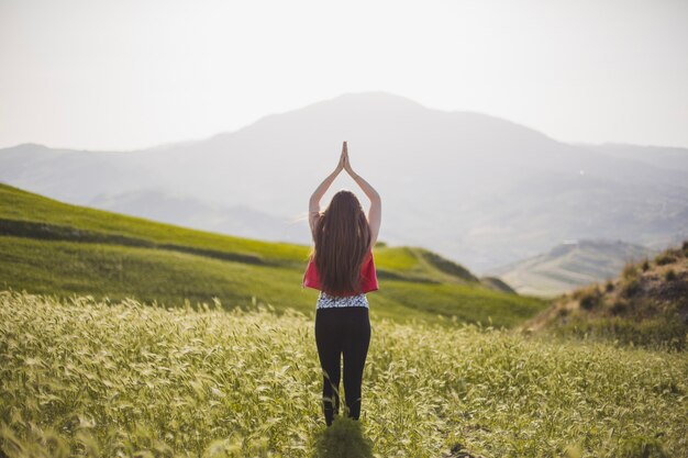 Donna in piedi e meditare sul campo