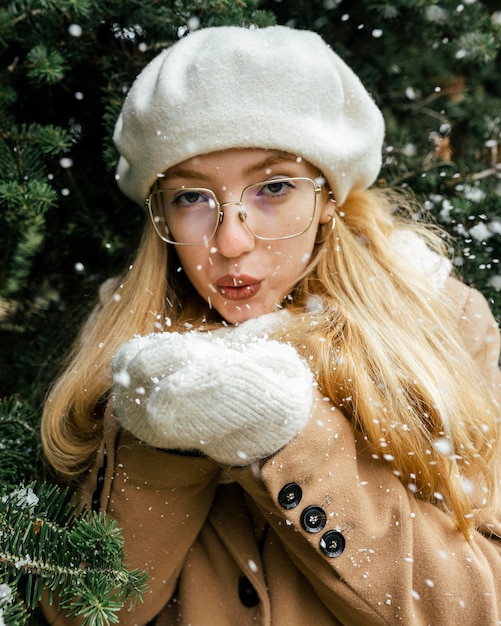 Donna in posa con vegetazione e neve che soffia al parco in inverno