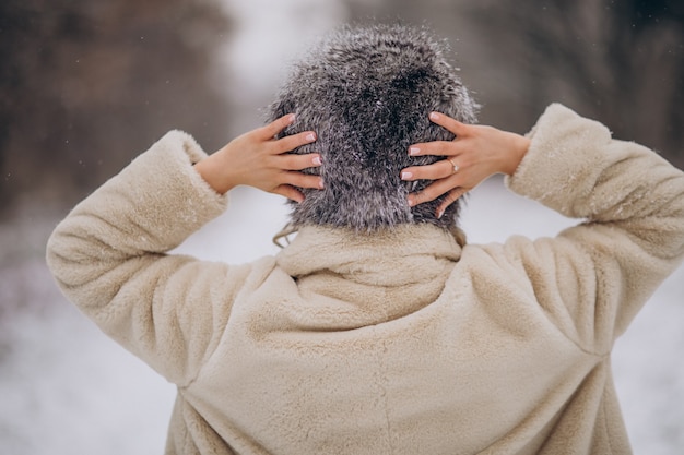 Donna in posa da dietro e cammina nel parco invernale