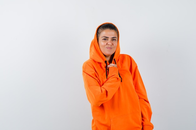 Donna in posa mentre indossa una felpa con cappuccio arancione e sembra affascinante