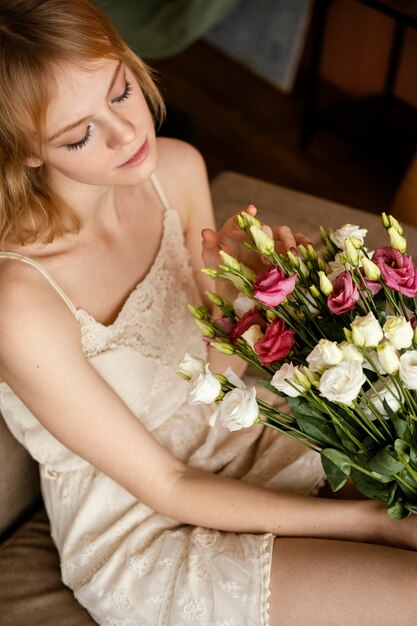 Donna in posa sul divano mentre si tiene il mazzo di fiori primaverili