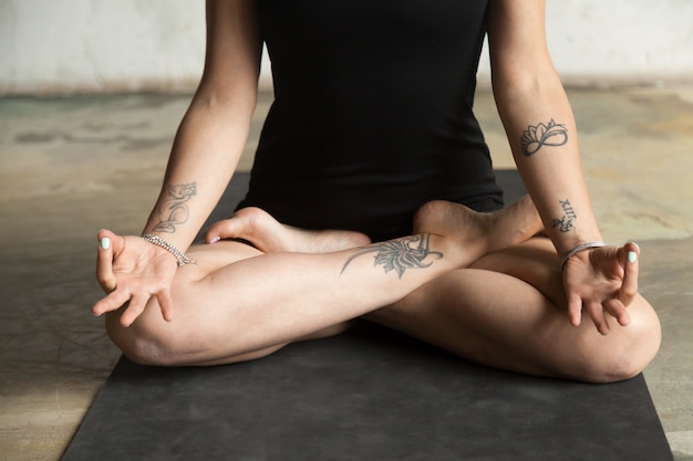 Donna in primo piano di posa di Padmasana, fondo del pavimento dello studio