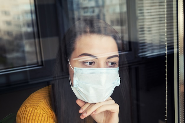 Donna in quarantena che indossa una maschera protettiva.