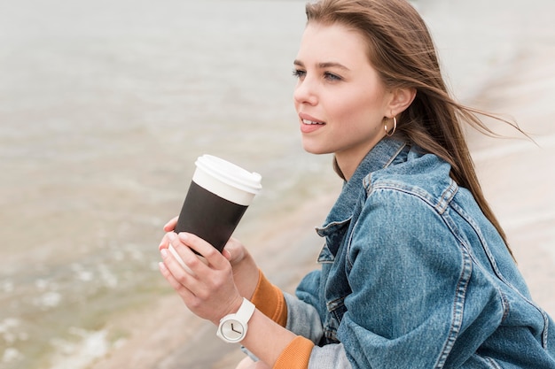 Donna in riva al mare con caffè