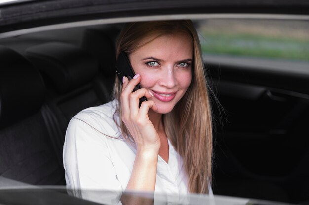 Donna in sedile posteriore auto parlando al telefono