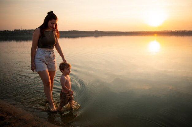 Donna in spiaggia con il suo bambino che si gode il tramonto