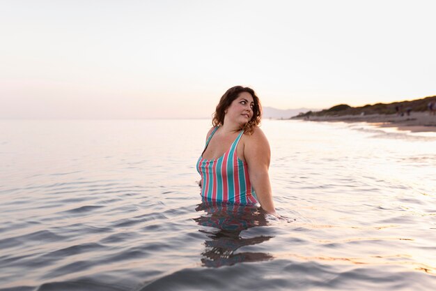 Donna in spiaggia nella posa dell'acqua