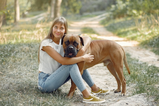 donna in un bosco estivo a giocare con il cane