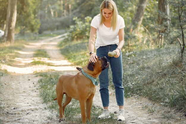 donna in un bosco estivo a giocare con il cane