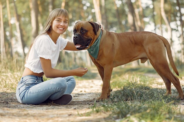 donna in un bosco estivo a giocare con il cane