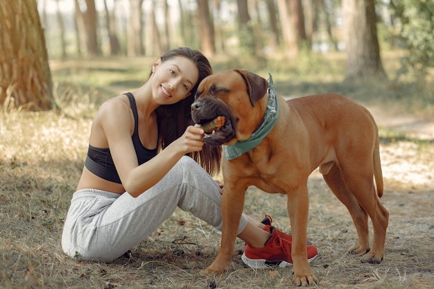 donna in un bosco estivo a giocare con il cane