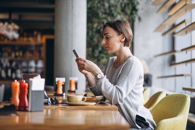 Donna in un caffè pranzando e parlando al telefono