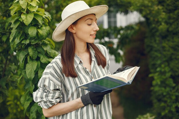 Donna in un cappello con un libro in un giardino