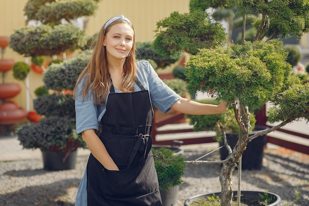 Donna in un grembiule nero che lavora in una serra