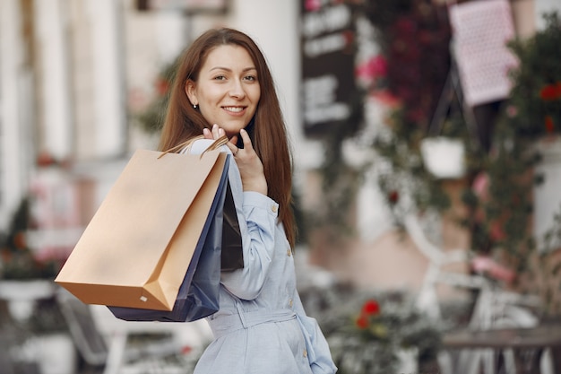 Donna in un vestito blu con il sacchetto della spesa in una città