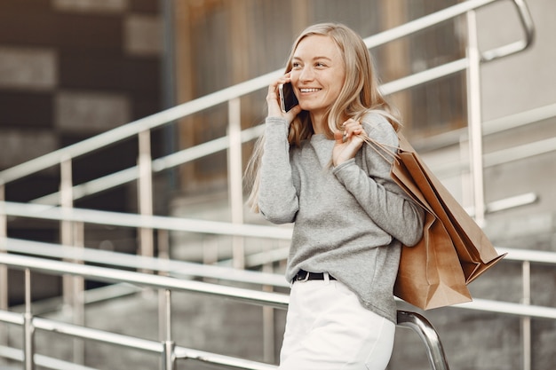 Donna in una città estiva. Signora con il cellulare. Donna in un maglione grigio.