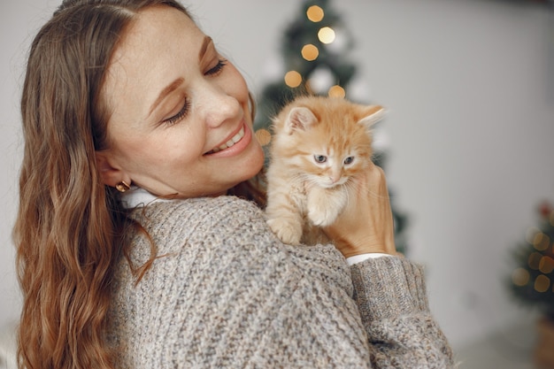 Donna in una stanza. Persona con un maglione grigio. Signora con piccolo gattino.