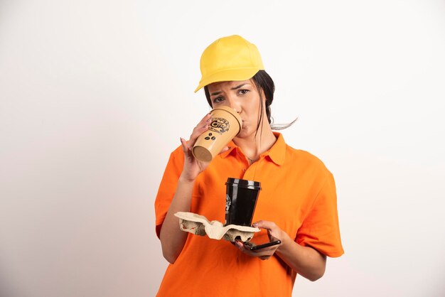 Donna in uniforme che beve da una tazza di caffè