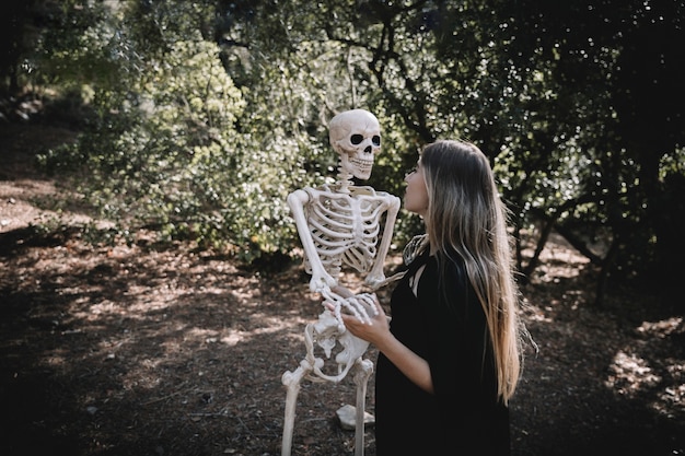 Donna in vestito della strega che tiene e che guarda attento allo scheletro