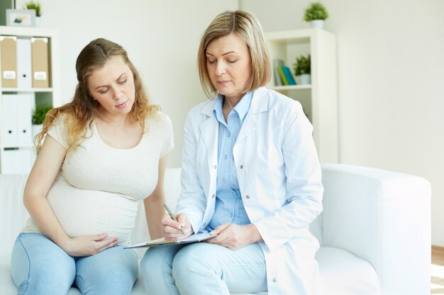 Donna incinta che comunica al suo medico in una stanza