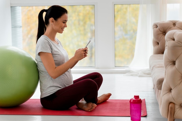 Donna incinta che controlla il suo telefono durante l'allenamento