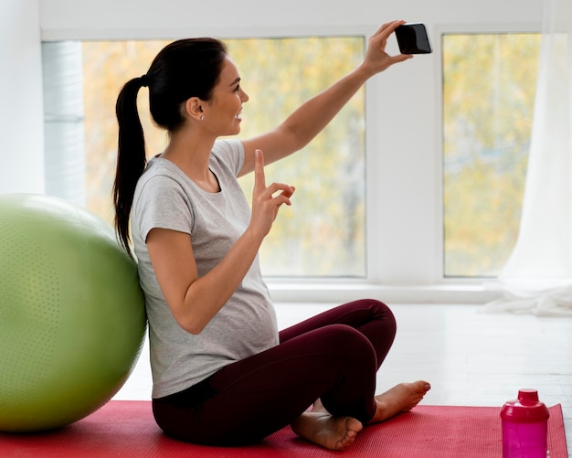 Donna incinta che prende un selfie accanto a una palla fitness